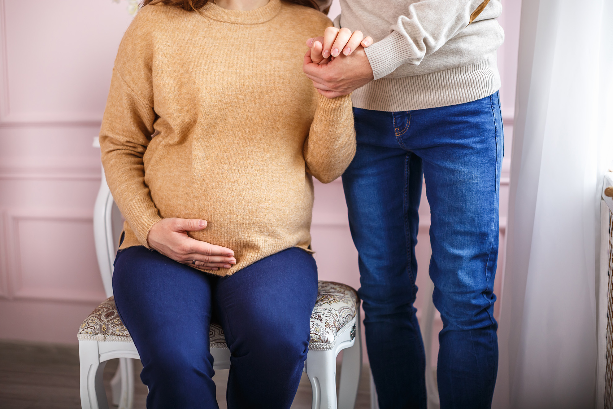 knitted booties in the hands of a pregnant woman next to her hus